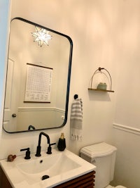 a bathroom with a toilet, sink and mirror